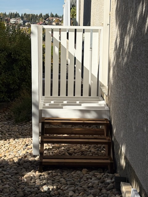 Painted wooden stair railing and steps beside a Calgary home by Calgary Repairs